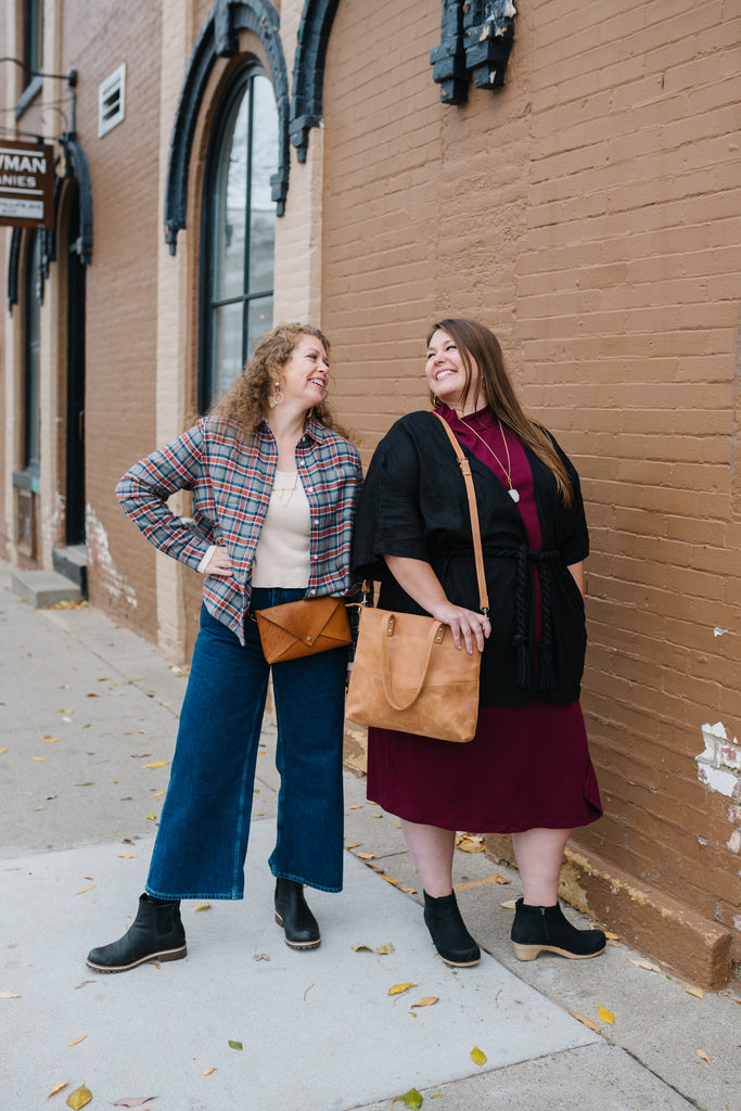 Two women dressed in sustainable and ethically made clothing from Terra Shepherd looking at each other and laughing - Sustainable and ethically made clothing including plus sizes.